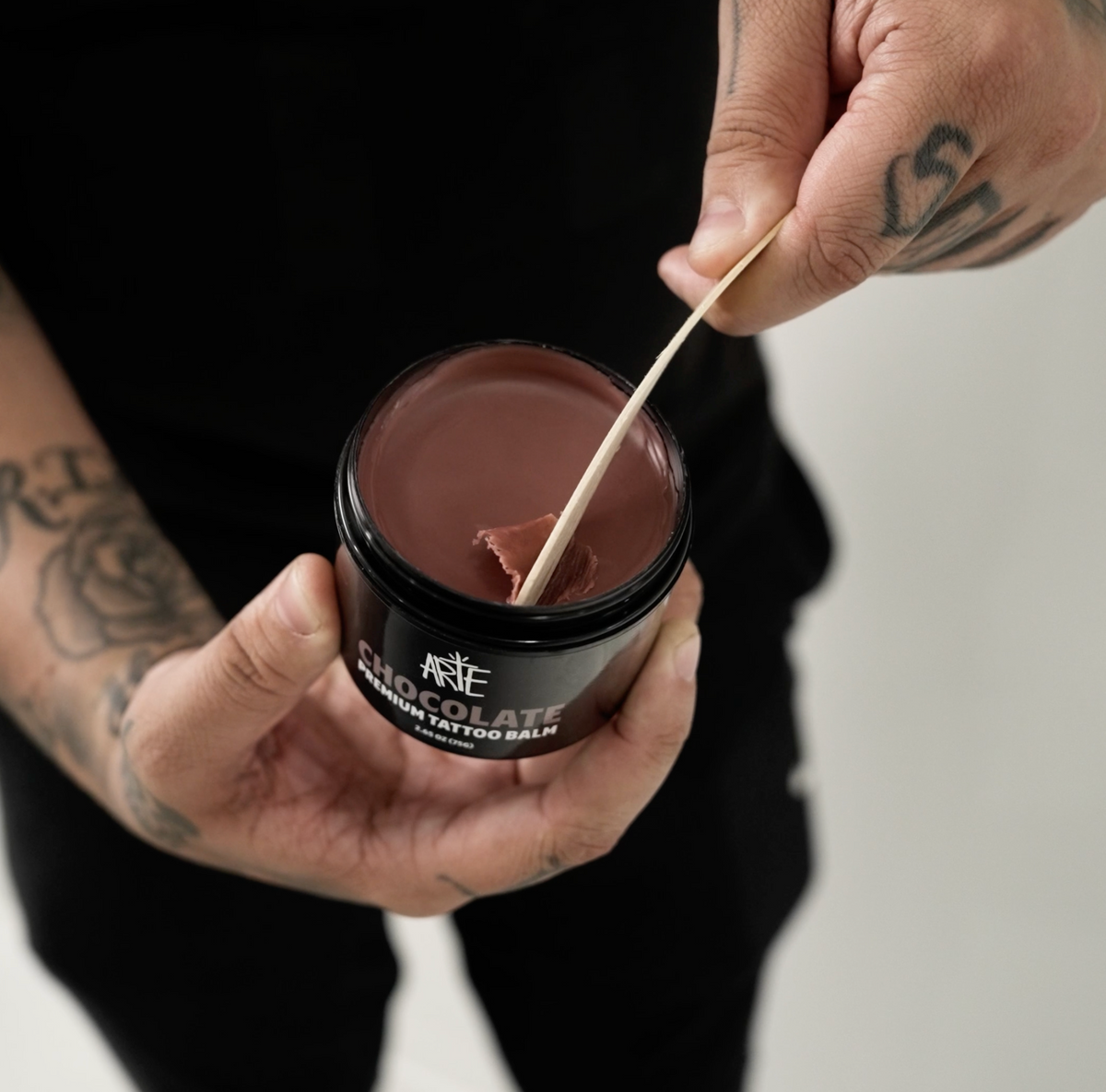The artist holding an open Chocolate jar and lifting a small amount with an applicator