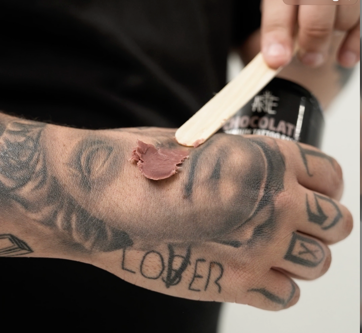 The same artist placing a small amount of Chocolate onto the back of his tattooed hand