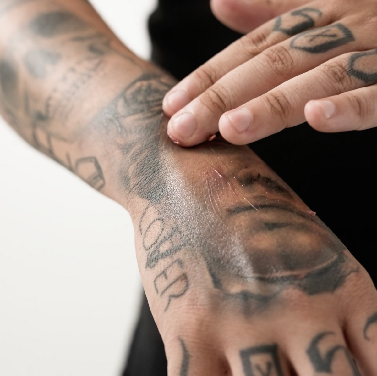 The same artist smoothing a thin layer of Chocolate balm over the same tattooed hand
